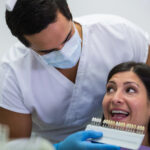 dentist examining female patient with teeth shades scale