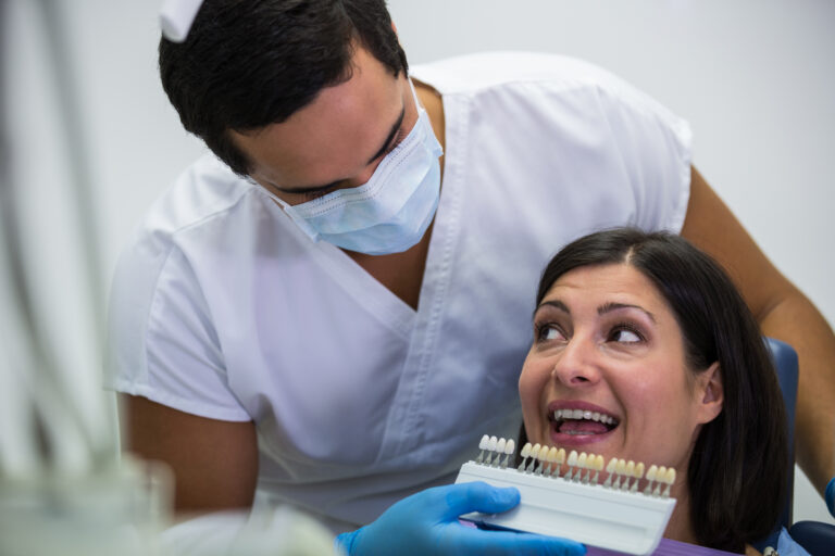 dentist examining female patient with teeth shades scale